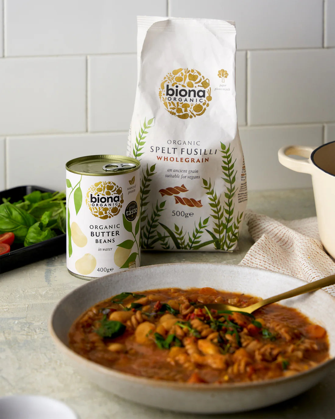 A bowl of hearty soup in the foreground with a bag and can of Biona Organic ingredients behind it on a kitchen counter.
