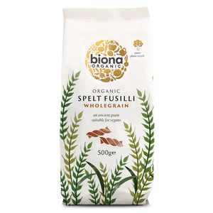 A 500g bag of Biona Organic Spelt Fusilli Wholegrain pasta on a solid white background. The packaging is off-white with a gold circular logo, green and olive botanical illustrations, and brown pasta pieces shown in the center.